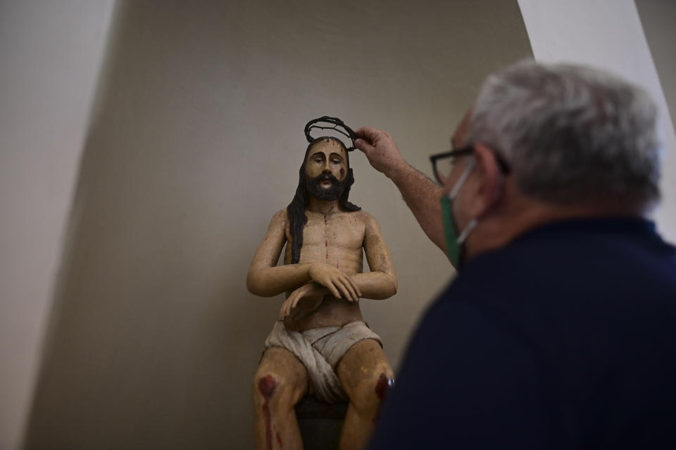 Architect Jorge Rigau arranges a crown of thorns on a statue of Jesus inside the San Jose Church, the second oldest Spanish church in the Americas, that will reopen following a massive reconstruction that took nearly two decades to complete, in San Juan, Puerto Rico, Tuesday, March 9, 2021. The church's construction began by 1532 on land donated by famous explorer Juan Ponce de León and whose base was erected atop an Indigenous settlement. (AP Photo/Carlos Giusti)