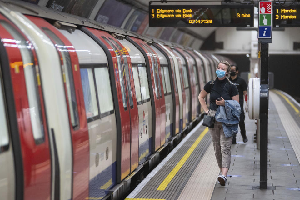 A commuter wearing a protective face mask walks along the platform at Clapham Common underground station, London, as train services increase this week as part of the easing of coronavirus lockdown restrictions, Thursday May 21, 2020. (Dominic Lipinski/PA via AP)