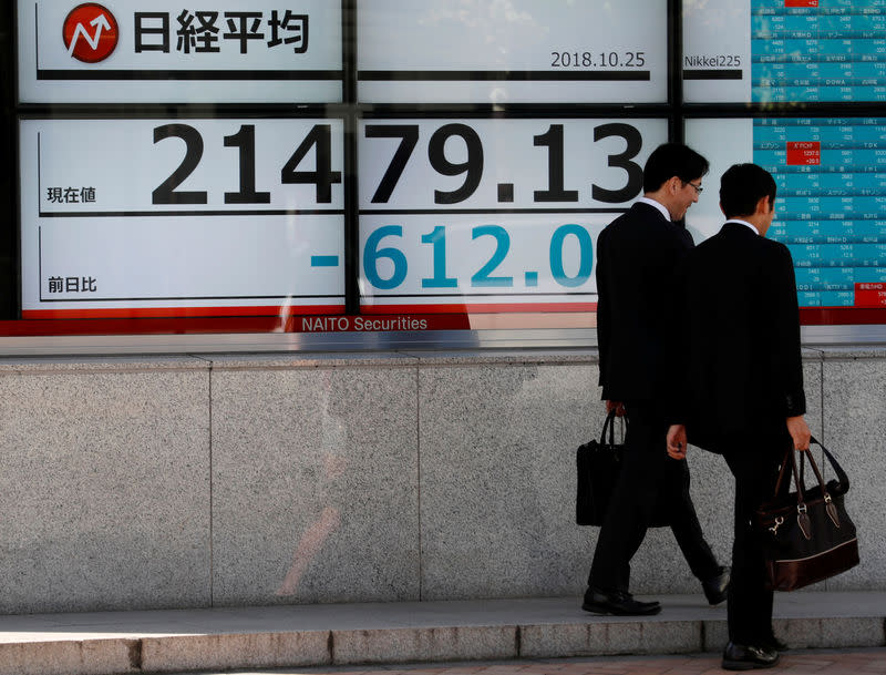 Men walk past an electronic board showing Japan's Nikkei average outside a brokerage in Tokyo, Japan, October 25, 2018. REUTERS/Kim Kyung-Hoon