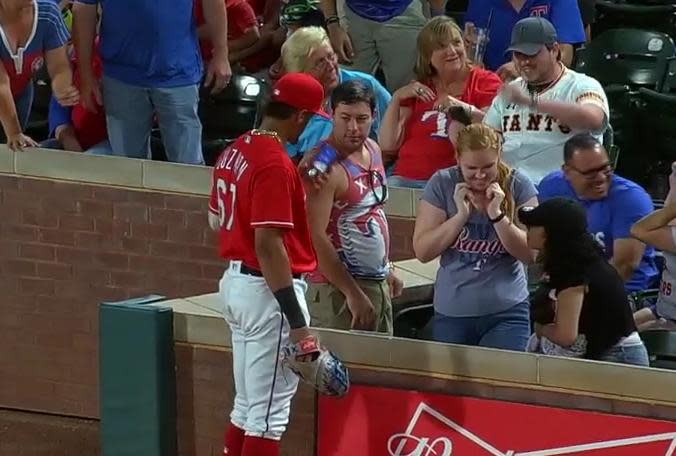 Texas Rangers rookie Ronald Guzman jokingly borrows a fan’s phone during Friday’s game against the Kansas City Royals. (MLB.TV)