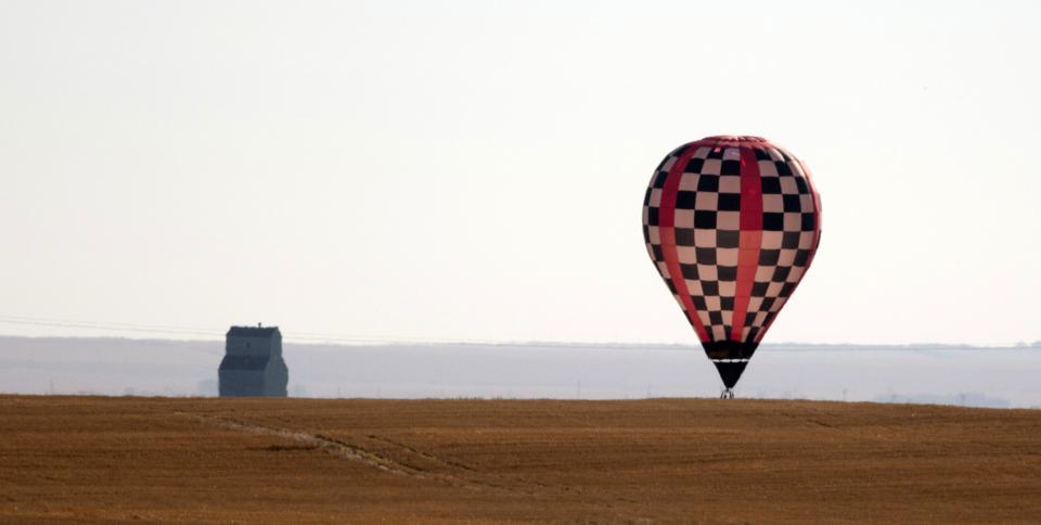 A hot air balloon prepares to land in a field east of High River