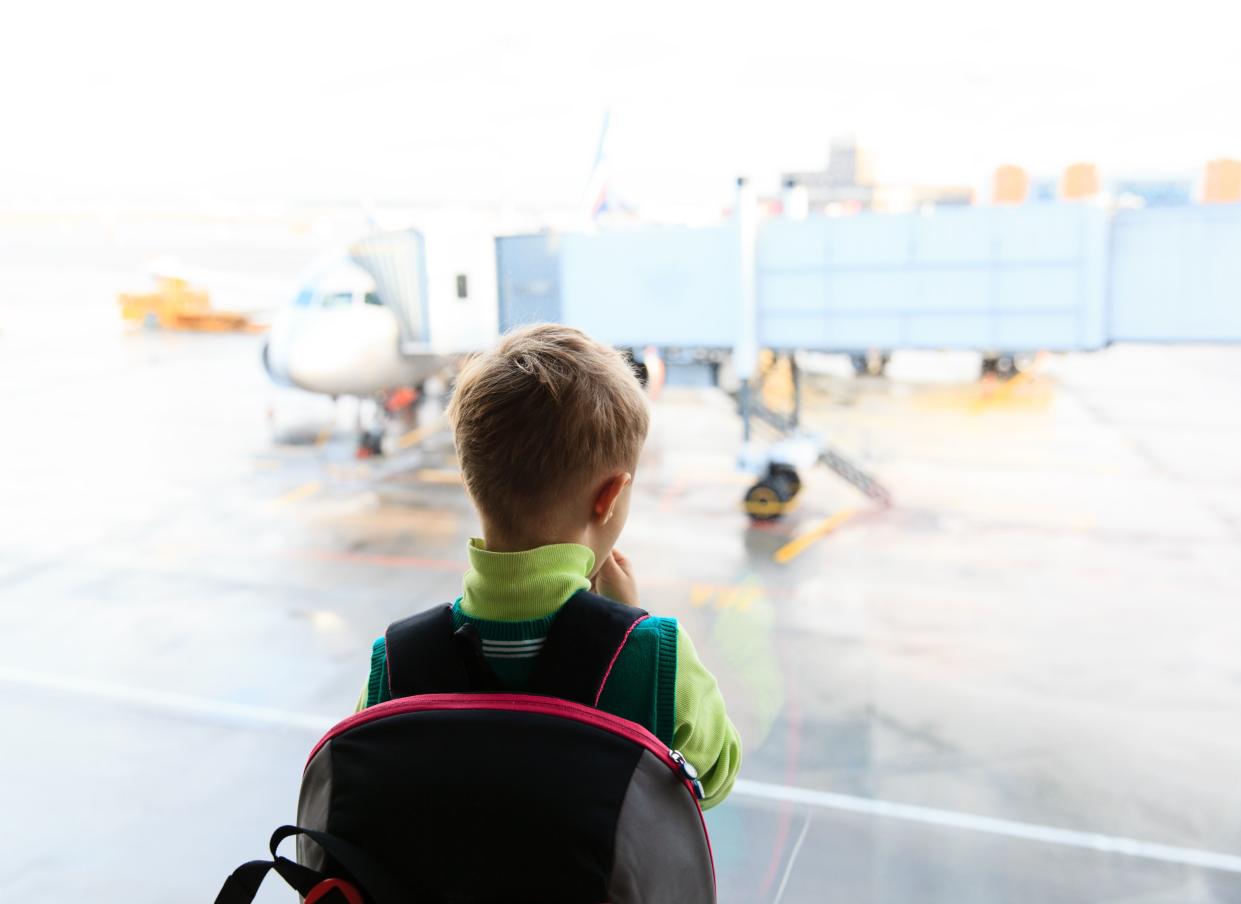 Stock photo of little boy looking at planes in the airport