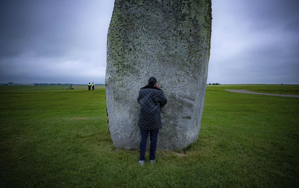 A man touches one of the standing stones during Summer Solstice at Stonehenge, where some people jumped over the fence to enter the stone-circle to watch the sun rise at dawn of the longest day of the year in the UK, in Amesbury, England, Monday June 21, 2021. The prehistoric monument of ancient stones have been officially closed for the celebrations due to the coronavirus lockdown, but groups of people ignored the lockdown to mark the Solstice, watched by low key security. (Ben Birchall/PA via AP)