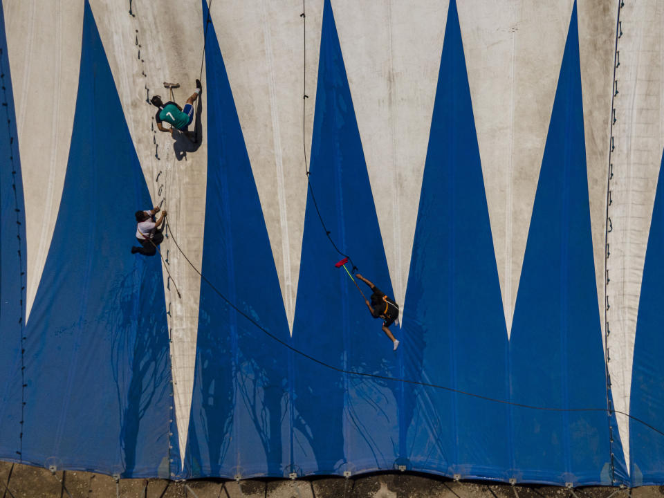 Bastián Rubio, segundo por la izquierda, y otros trabajadores limpian una parte de la carpa del Circo Timoteo, a las afueras de Santiago, Chile, el 15 de diciembre de 2022. Nieto adoptivo del fundador del circo, René Valdés, Rubio se encarga de la limpieza e instalación de la lona, además de actuar como músico, malabaristas, trapecista y payaso. (AP Foto/Esteban Félix)