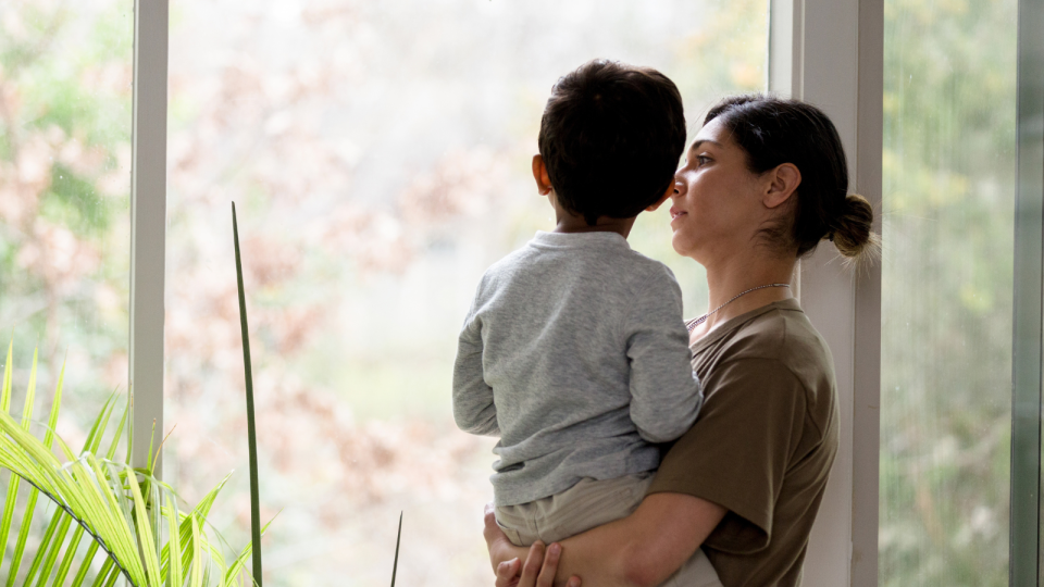 A mother and son look out a window to represent Charlotte splitting with her partner and trying to live under the same roof because of the rent crisis.