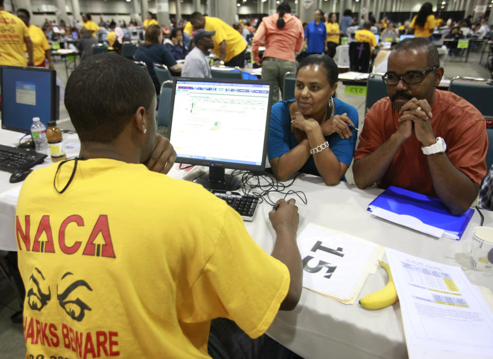 Charles Gibson, right, and his wife, Michelle, sit across from Carral DuPont, left, who is seated at a screen and wearing a yellow T-shirt saying NACA Sharks Beware.to get a reduction on their upside down loan for their Riverside, Calif. home, at the Los Angeles Convention Center in downtown Los Angeles on Thursday, Sept. 30, 2010. (Damian Dovarganes/AP Photo)