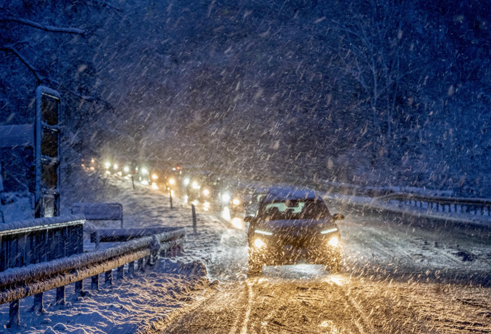 Commuters queue in heavy snowfalls on a country road in a forest of the Taunus region near Frankfurt, Germany, early Tuesday, Nov. 28, 2023. (AP Photo/Michael Probst)