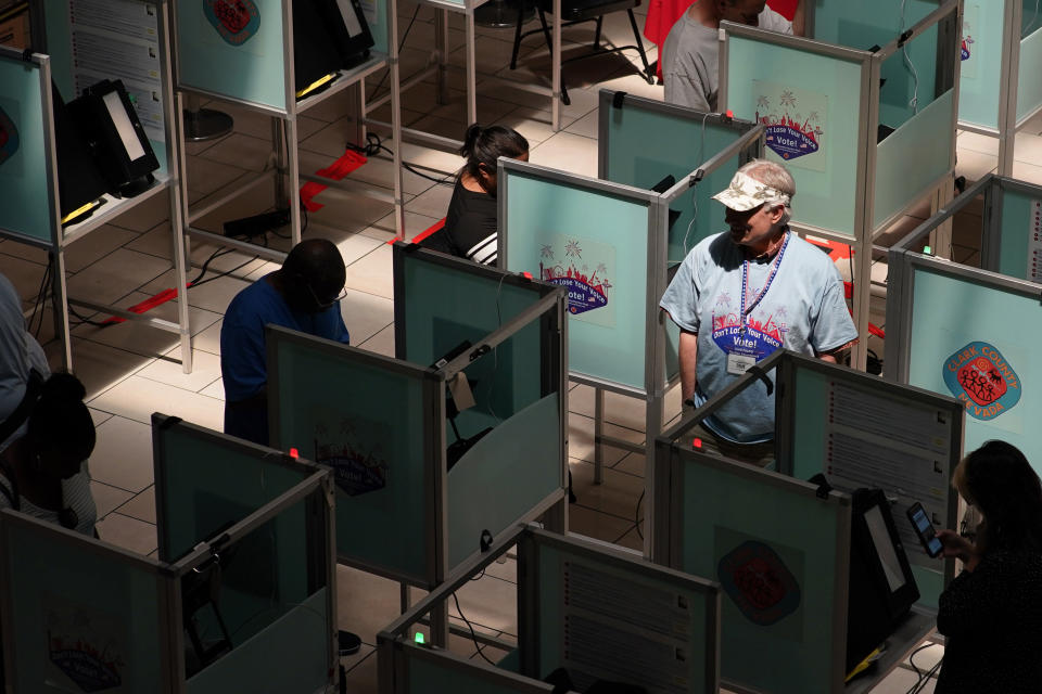 FILE - An election worker walks through voting booths to help as people vote at a polling place June 14, 2022, in Las Vegas. Voting could feel different in this year's midterms, as the election falsehoods told by former President Donald Trump and many of his supporters have created a ripple effect across the country. (AP Photo/John Locher, File)