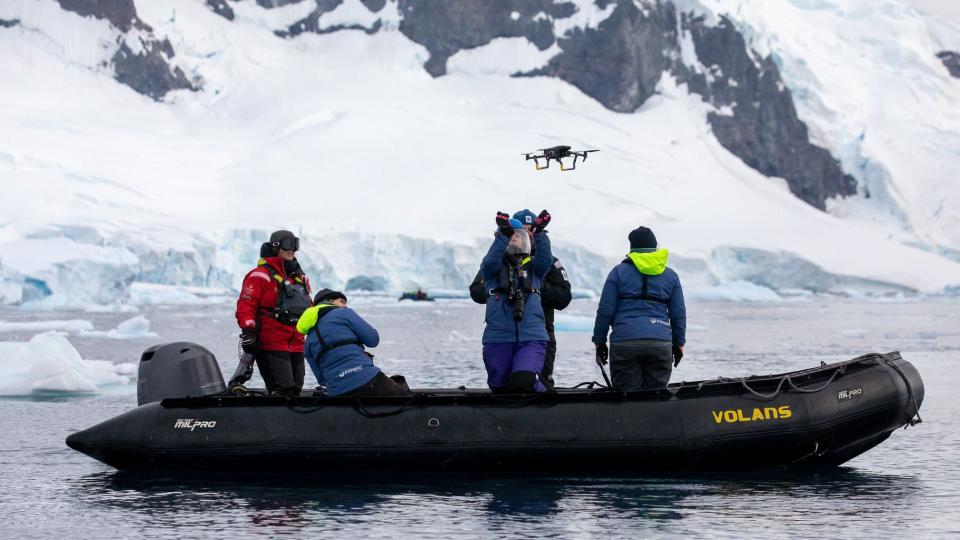 A scientist on a small, inflatable research boat prepares to catch a drone in Antarctica