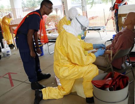 Centers for Disease Control and Prevention (CDC) instructor Satish Pillai (L) gives guidance to Paul Reed (front on R), chief medical officer for the U.S. Public Health Service, and Roseda Marshall, chairman of pediatrics at the University of Liberia's A.M. Dogliotti College of Medicine, in preparation for the response to the current Ebola outbreak, during a CDC safety training course in Anniston, Alabama, October 6, 2014. REUTERS/Tami Chappell