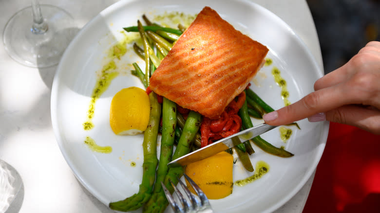 Person eating asparagus and salmon
