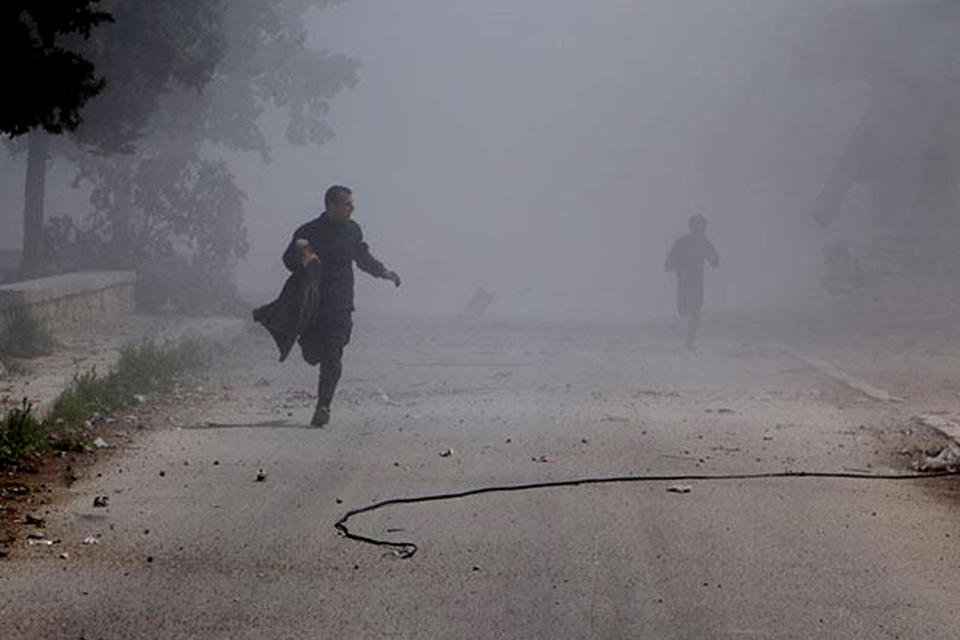 In this photo provided by the anti-government activist group Aleppo Media Center (AMC), which has been authenticated based on its contents and other AP reporting, Syrian residents run in the street after a government warplane dropped barrel bombs at al-Sakhour neighborhood, in Aleppo, Syria, Saturday, April 5, 2014. The leader of al-Qaida, Ayman al-Zawahri , called on Syrian militant groups to determine who killed his representative in the country, a man many fighters believe died at the hands of a rival militia. (AP Photo/Aleppo Media Center, AMC)