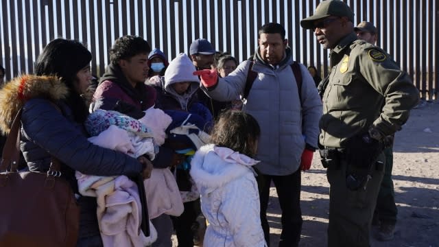 Migrants talking to a border patrol agent
