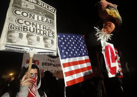 A protester, rallying against layoffs holds a placard that reads "With Lear against the vultures" next to a mock vulture, in front of the factory of U.S. automotive supplier Lear on the outskirts of Buenos Aires July 30, 2014. REUTERS/Enrique Marcarian