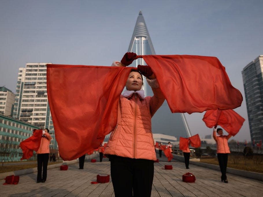 Members of a Socialist Women's Union propaganda troupe perform in front of the Ryugyong Hotel in 2019.