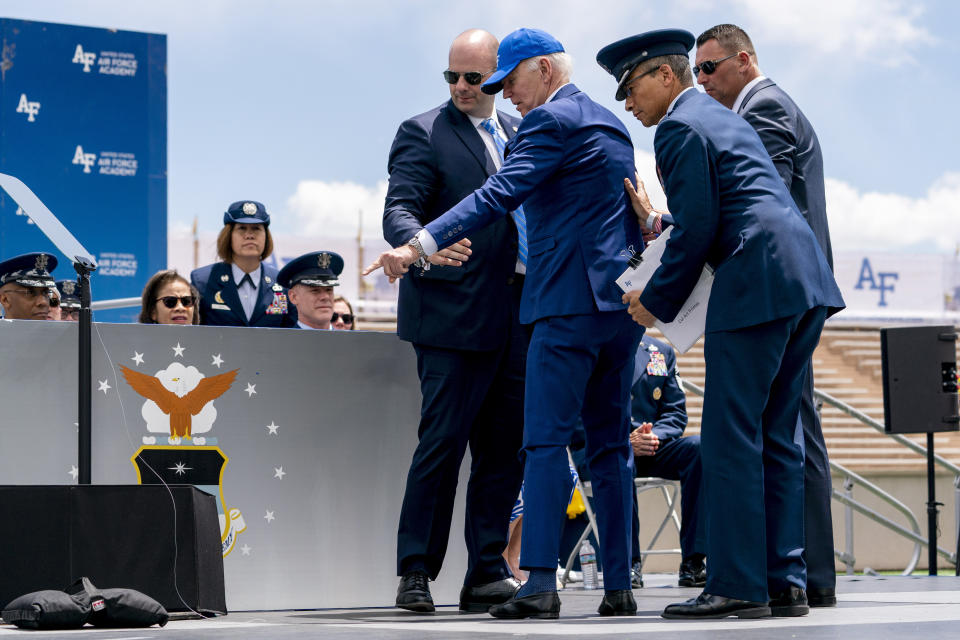 President Joe Biden points to sandbags after falling on stage during the 2023 United States Air Force Academy Graduation Ceremony at Falcon Stadium, Thursday, June 1, 2023, at the United States Air Force Academy in Colorado Springs, Colo. (AP Photo/Andrew Harnik)