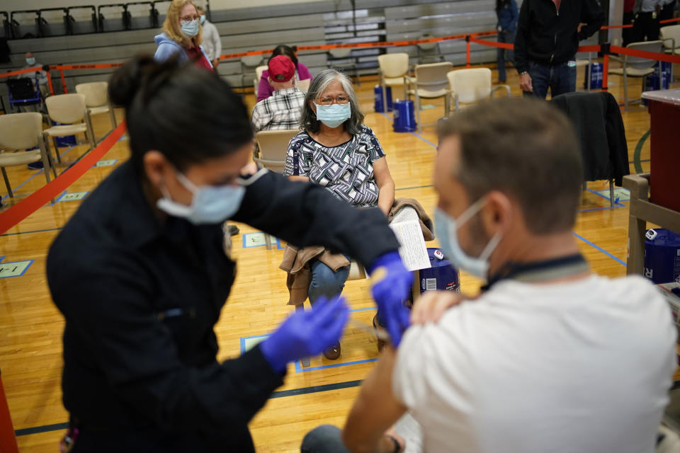 FILE - In this Feb. 17, 2021, file photo, people receive the COVID-19 vaccine at a vaccination site in Las Vegas. States are working quickly get the coronavirus vaccine into people’s arms after last week’s icy storms, freezing temperatures and widespread power outages closed clinics and slowed vaccine deliveries nationwide. (AP Photo/John Locher, File)