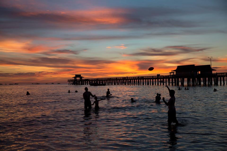 People hang out on the beach before the fireworks show to celebrate Independence Day at the Naples Pier on July 4, 2017.