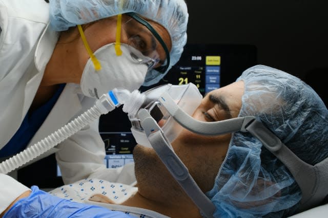 Female doctor checking on Covid-19 infected patient while connected to a ventilator