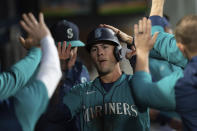 Seattle Mariners Dylan Moore is congratulated by teammates in the dugout after he scored against the Oakland Athletics during the first inning of a baseball game Friday, Sept. 30, 2022, in Seattle. (AP Photo/Stephen Brashear)