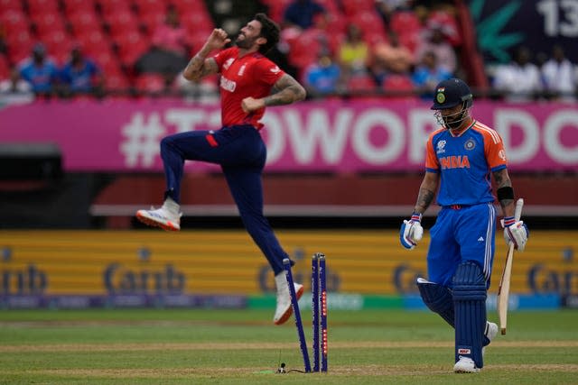 Reece Topley jumps to celebrates the dismissal of Virat Kohli, who walks off the field