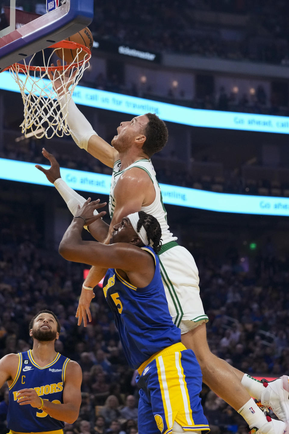 Boston Celtics center Blake Griffin, top, taps the ball into the basket over Golden State Warriors center Kevon Looney during the first half of an NBA basketball game in San Francisco, Saturday, Dec. 10, 2022. (AP Photo/Godofredo A. Vásquez)