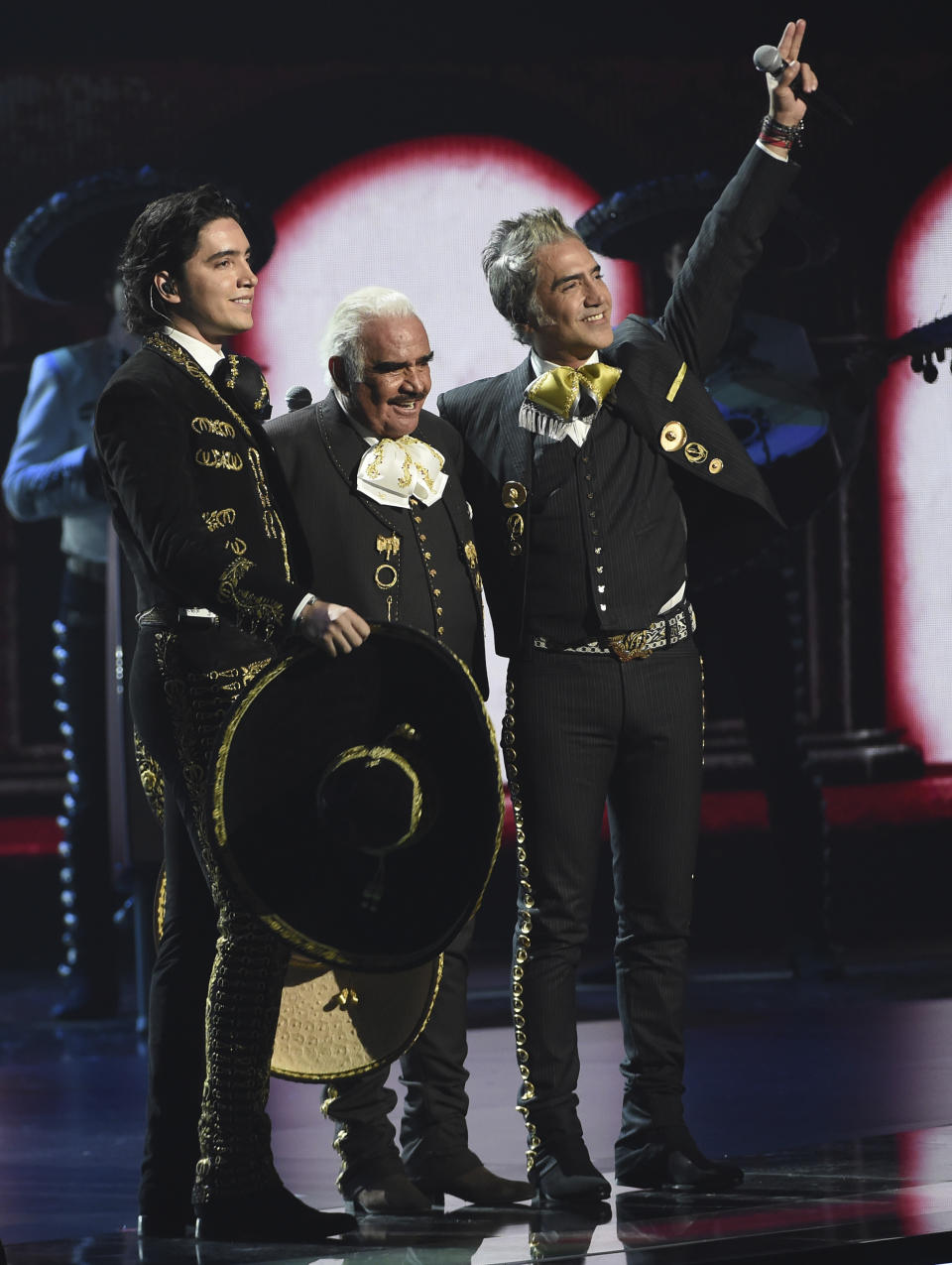 Vicente Fernandez, center, his son Alejandro Fernandez, right, and his grandson Alex Fernandez react after performing a medley at the 20th Latin Grammy Awards on Thursday, Nov. 14, 2019, at the MGM Grand Garden Arena in Las Vegas. (AP Photo/Chris Pizzello)