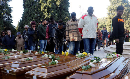 People pay respect as they walk by the coffins ahead of the funeral service for 26 Nigerian women who died last week while crossing the Mediterranean Sea, at the Salerno cemetery, Italy, November 17, 2017. REUTERS/Ciro De Luca