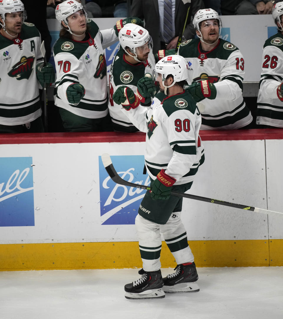 Minnesota Wild left wing Marcus Johansson, front, is congratulated as he passes the team box after scoring a goal against the Colorado Avalanche in the first period of an NHL hockey game, Wednesday, March 29, 2023, in Denver. (AP Photo/David Zalubowski)