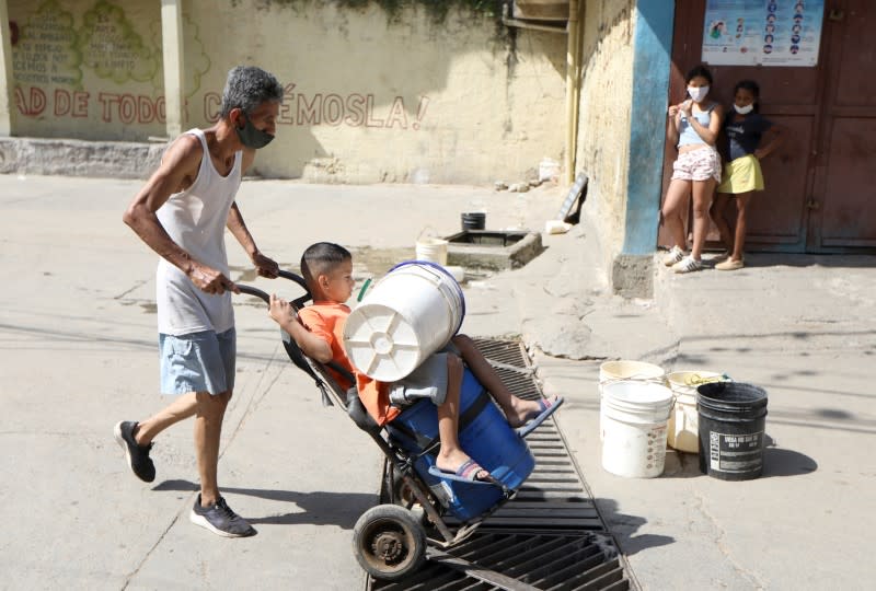 A man carries a child over a wheelbarrow near an unknown water source in the low-income neighbourhood of Petare amid the coronavirus disease (COVID-19) outbreak in Caracas