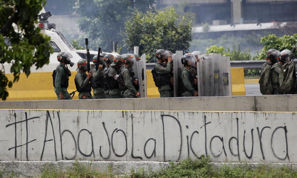 The Spanish message ‘Down with the dictatorship’ covers a highway wall where security forces block an opposition march from reaching the National Electoral Council headquarters in Caracas.
