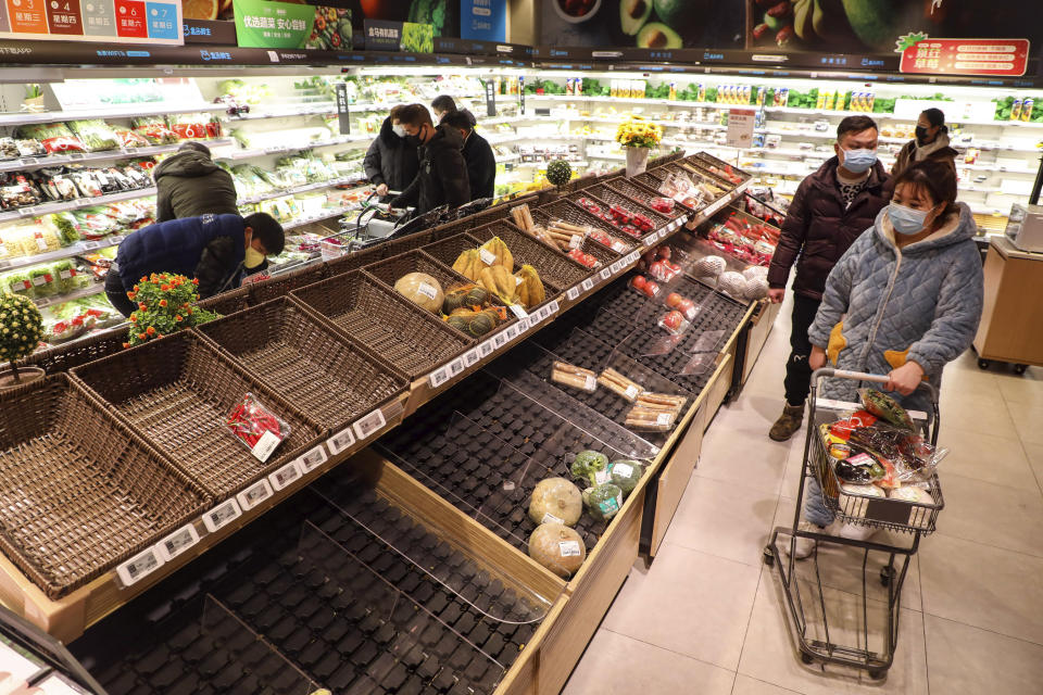 FILE - In this Jan. 25, 2020, file photo, shoppers wearing face masks look for groceries with many empty shelves at a supermarket in Wuhan in central China's Hubei province. The Chinese city of Wuhan is looking back on a year since it was placed under a 76-day lockdown beginning Jan. 23, 2020. (Chinatopix via AP, File)