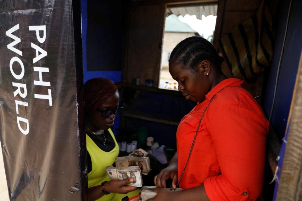Peace stands with her sister, Joy Ekwere, in her point of sale kiosk in Uyo (Reuters)