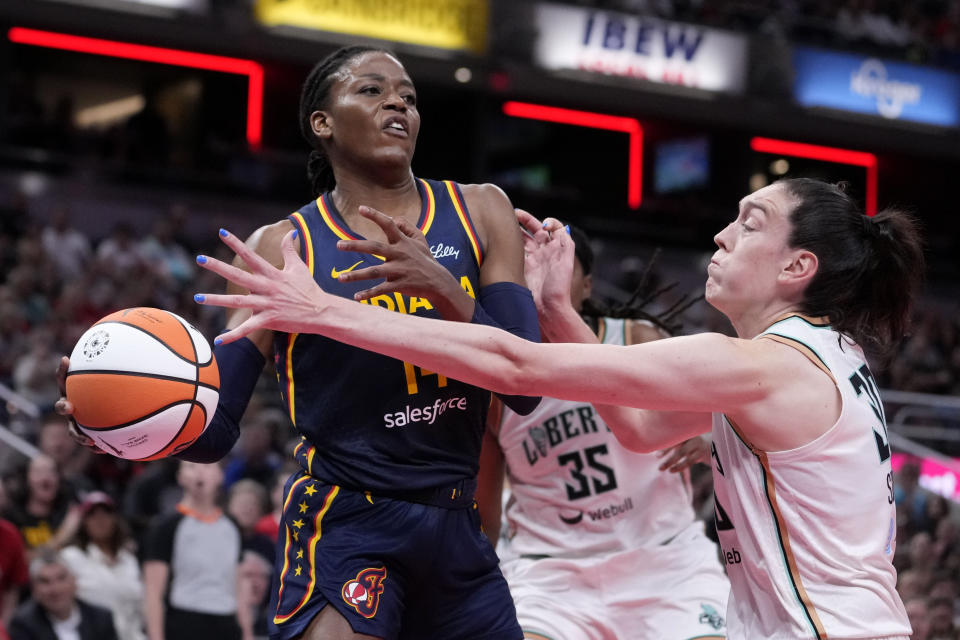 Indiana Fever center Temi Fagbenle (14) passes over New York Liberty forward Breanna Stewart (30) in the second half of a WNBA basketball game, Thursday, May 16, 2024, in Indianapolis. (AP Photo/Michael Conroy)