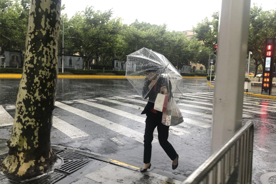 A woman carrying an umbrella braces against the wind and rain as Typhoon In-fa sweeps through Shanghai in China Sunday, July 25, 2021. Typhoon In-fa hit China's east coast south of Shanghai on Sunday after people living near the sea were evacuated, airline flights and trains were canceled and the public was ordered to stay indoors. (AP Photo/Chen Si)