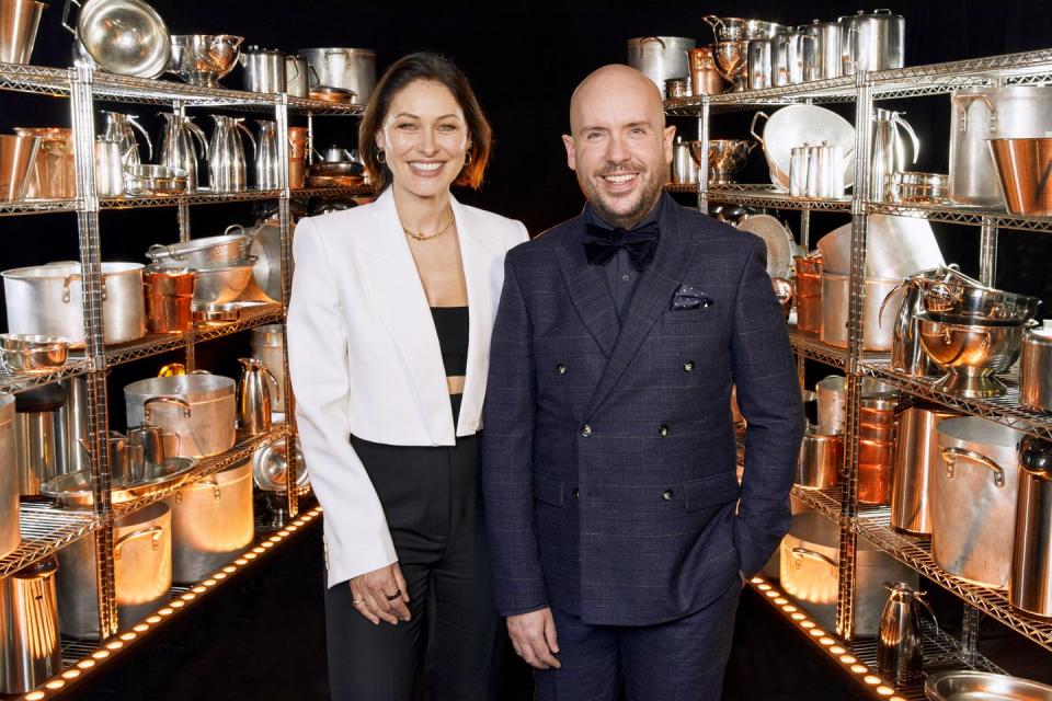 emma willis, wearing a white jacket and black pantsuit, and tom allen, wearing a blank suit, on the set of cooking with the stars