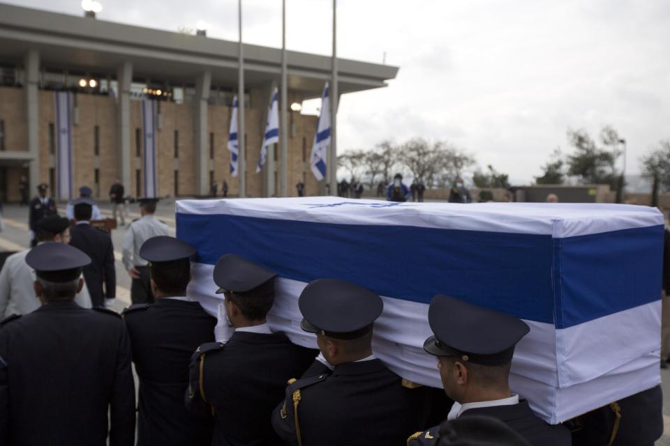 Members of the Knesset guard carry the coffin of late Israeli Prime Minister Ariel Sharon at the Knesset, Israel's Parliament, in Jerusalem, Sunday, Jan. 12, 2014. Sharon, the hard-charging Israeli general and prime minister who was admired and hated for his battlefield exploits and ambitions to reshape the Middle East, died Saturday, eight years after a stroke left him in a coma from which he never awoke. He was 85. (AP Photo/Sebastian Scheiner)
