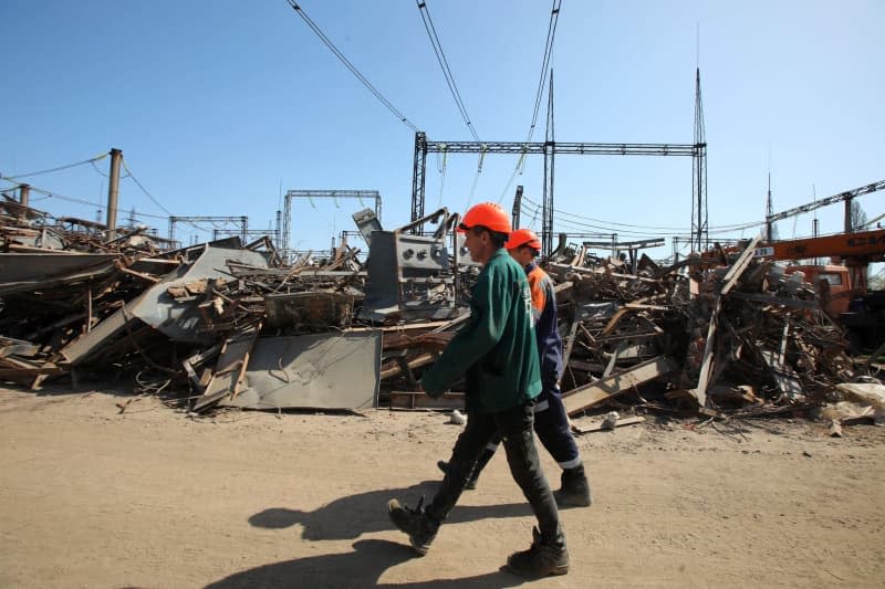 Utility workers walk past a pile of rubble at a power plant damaged by Russian shelling. -/Ukrinform/dpa