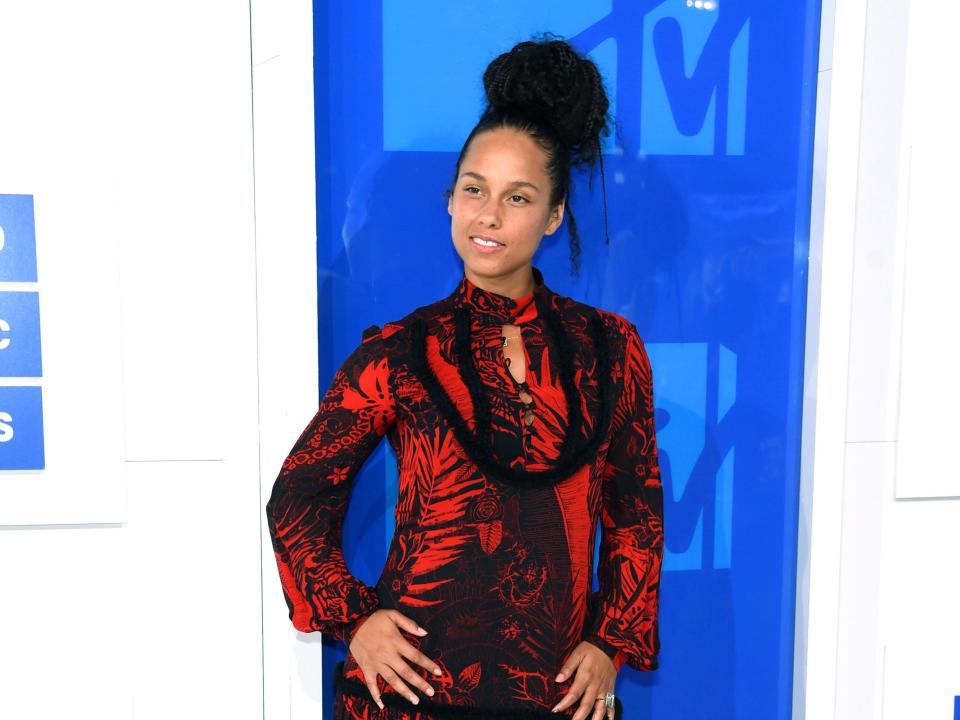 Alicia Keys posing in a red gown in front of an MTV backdrop.
