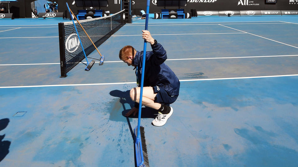 Australian Open staff, pictured here cleaning the dirt off the outside courts.