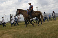A prison guard rides a horse alongside prisoners as they return from farm work detail, Aug. 18, 2011, at the Louisiana State Penitentiary in Angola, La. Almost all of the country's state and federal adult prisons have some sort of work programs, employing around 800,000 people, according to a 2022 report by the American Civil Liberties Union. (AP Photo/Gerald Herbert)