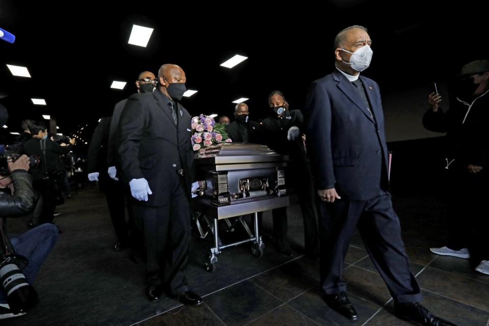 Pall bearers wheel a casket