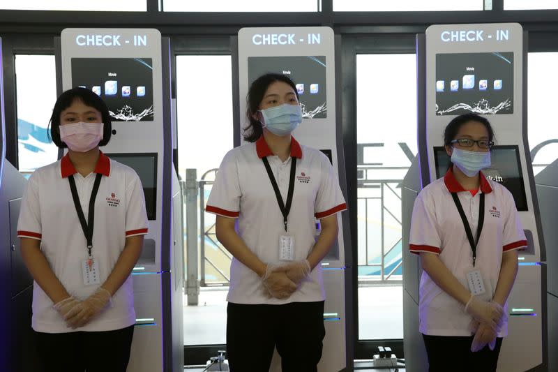 Staff wearing face masks and gloves prepare to help passengers check in at the Explorer Dream cruise ship in Keelung