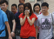 A woman, center, who lost her mother in a ferry collision, leaves a public mortuary with relatives of other victims, in Hong Kong Tuesday, Oct. 2, 2012. A ferry on Monday collided with a boat owned by utility company Power Assets Holdings Ltd., which was taking its workers and their families to famed Victoria Harbor to watch a fireworks display in celebration of China's National Day and mid-autumn festival, killing at least 36 people. (AP Photo/Kin Cheung)