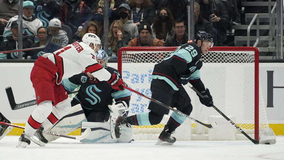 Seattle Kraken defenseman Vince Dunn (29) works to clear the puck as Carolina Hurricanes right wing Nino Niederreiter, left, and Kraken goaltender Philipp Grubauer watch during the first period of an NHL hockey game Wednesday, Nov. 24, 2021, in Seattle. (AP Photo/Ted S. Warren)