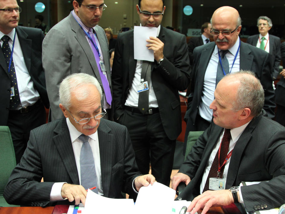 Cypriot Finance Minister and President of the rotating EU Council Vassos Chiarly, bottom left, reads a document , as he is surrounded by unidentified delegation members, during the EU finance ministerial meeting at the European Council building in Brussels, Tuesday, July 10, 2012. Euro area finance ministers agreed early Tuesday on the terms of a bailout for Spain's troubled banks, saying that 30 billion euro ($36.88 billion) can be ready by the end of this month. (AP Photo/Yves Logghe)