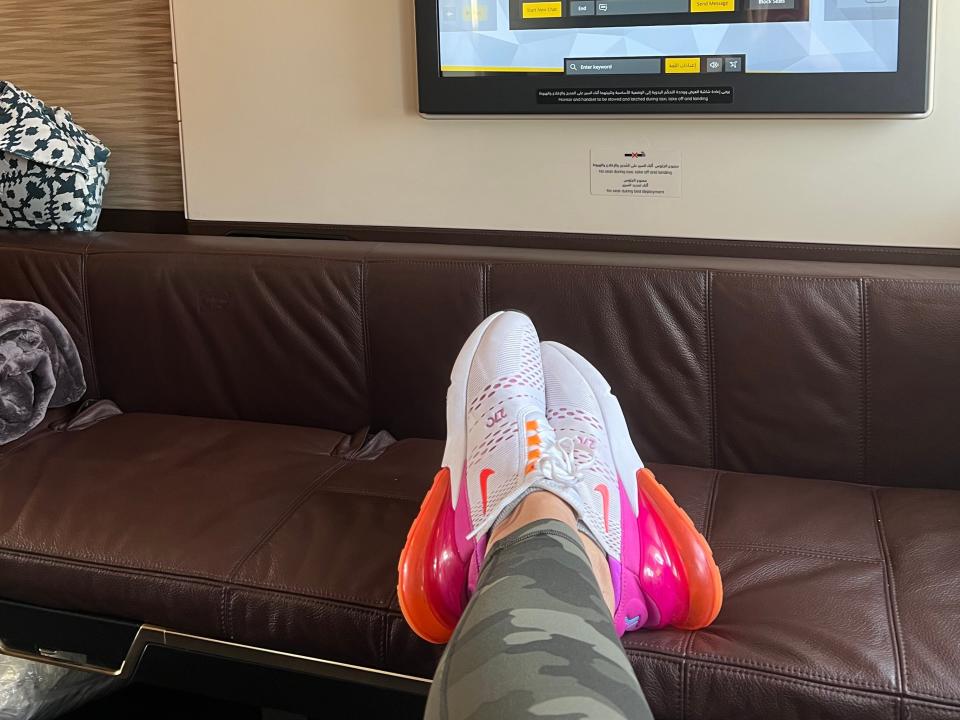 Someone's feet resting on a couch in front of a TV.