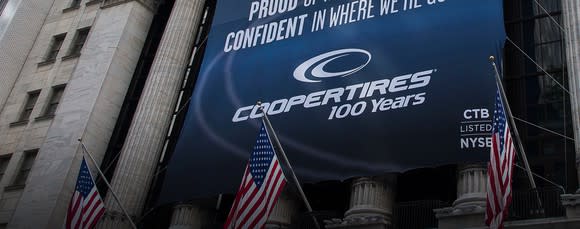 Banner with Cooper Tire logo and slogan hanging from New York Stock Exchange pillars.