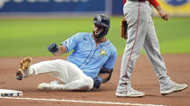 Tampa Bay Rays' Amed Rosario slides past Los Angeles Angels third baseman Anthony Rendon with an RBI triple during the first inning of a baseball game Thursday, April 18, 2024, in St. Petersburg, Fla. Rays' Richie Palacios scored on the play. (AP Photo/Chris O'Meara)