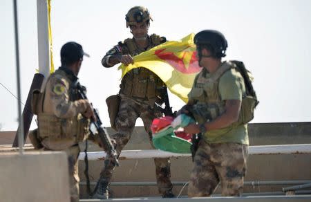 A member of the Iraqi security forces holds a Kurdish flag in Kirkuk, Iraq October 16, 2017. REUTERS/Stringer